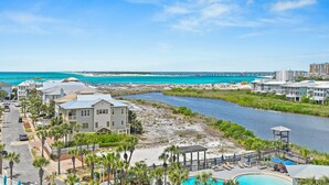 A coastal hotel with a swimming pool, beachfront view, and a river running through the property. - Sunset Jetty View! Enjoy one free beach chair set up and umbrella each day! (Destin)
