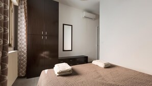 Um quarto com cama, guarda-roupa, espelho e aparelho de ar condicionado.