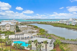 A resort with a swimming pool, beachfront view, and a pier extending into the water.