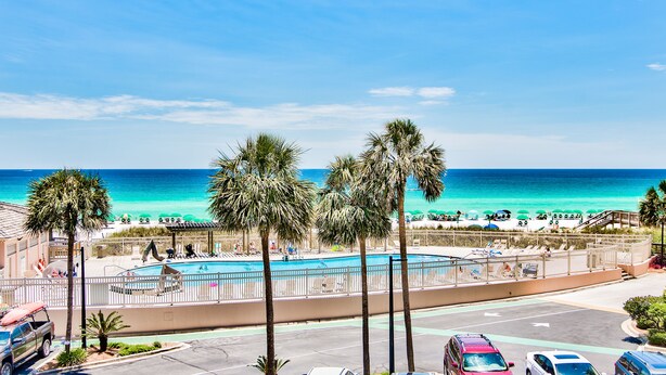 Un hôtel situé en bord de mer, doté d’une piscine, de palmiers et offrant une vue sur l’océan.