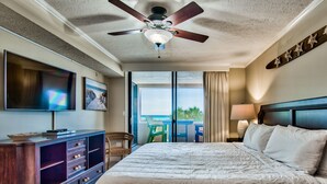 Une chambre d’hôtel avec un lit, une télévision, un ventilateur de plafond et une vue sur l’océan.