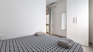 Un dormitorio con una colcha estampada, un armario y un equipo de aire acondicionado.