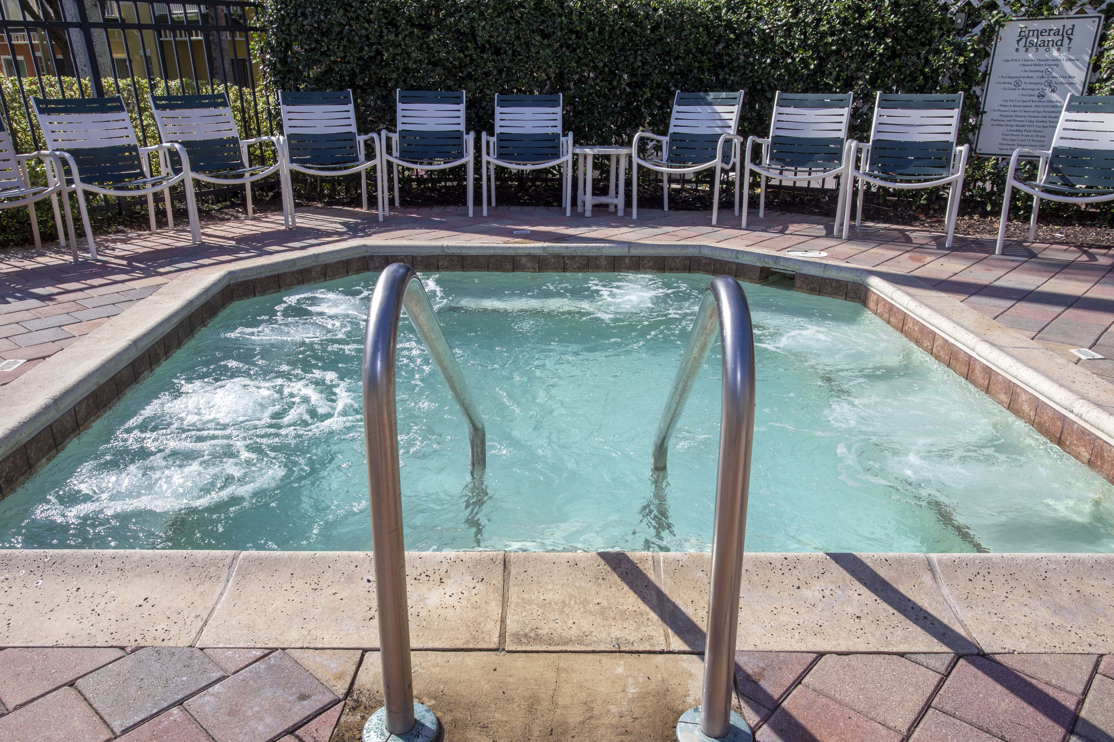 A swimming pool with a metal ladder, surrounded by lounge chairs and a sign indicating 'Emerald Island'.