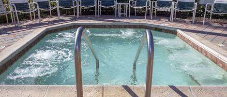 A swimming pool with a metal ladder, surrounded by lounge chairs and a sign indicating 'Emerald Island'.