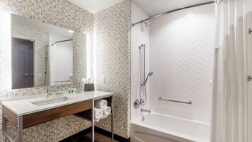 A modern bathroom with a white sink, mirror, shower, and herringbone-patterned walls.