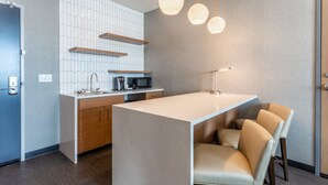 A modern kitchen with a central island, wooden cabinets, a microwave, and a coffee machine. - Holiday Inn & Suites Cedar Falls - Waterloo Event Ctr by IHG (Cedar Falls)
