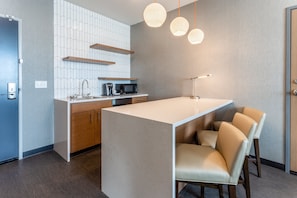 Een moderne keuken met een centraal eiland, houten kastjes, een magnetron en een koffieapparaat.