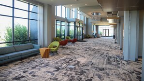 A spacious lobby with a patterned carpet, a long sofa, and several colorful chairs. - Holiday Inn & Suites Cedar Falls - Waterloo Event Ctr by IHG (Cedar Falls)