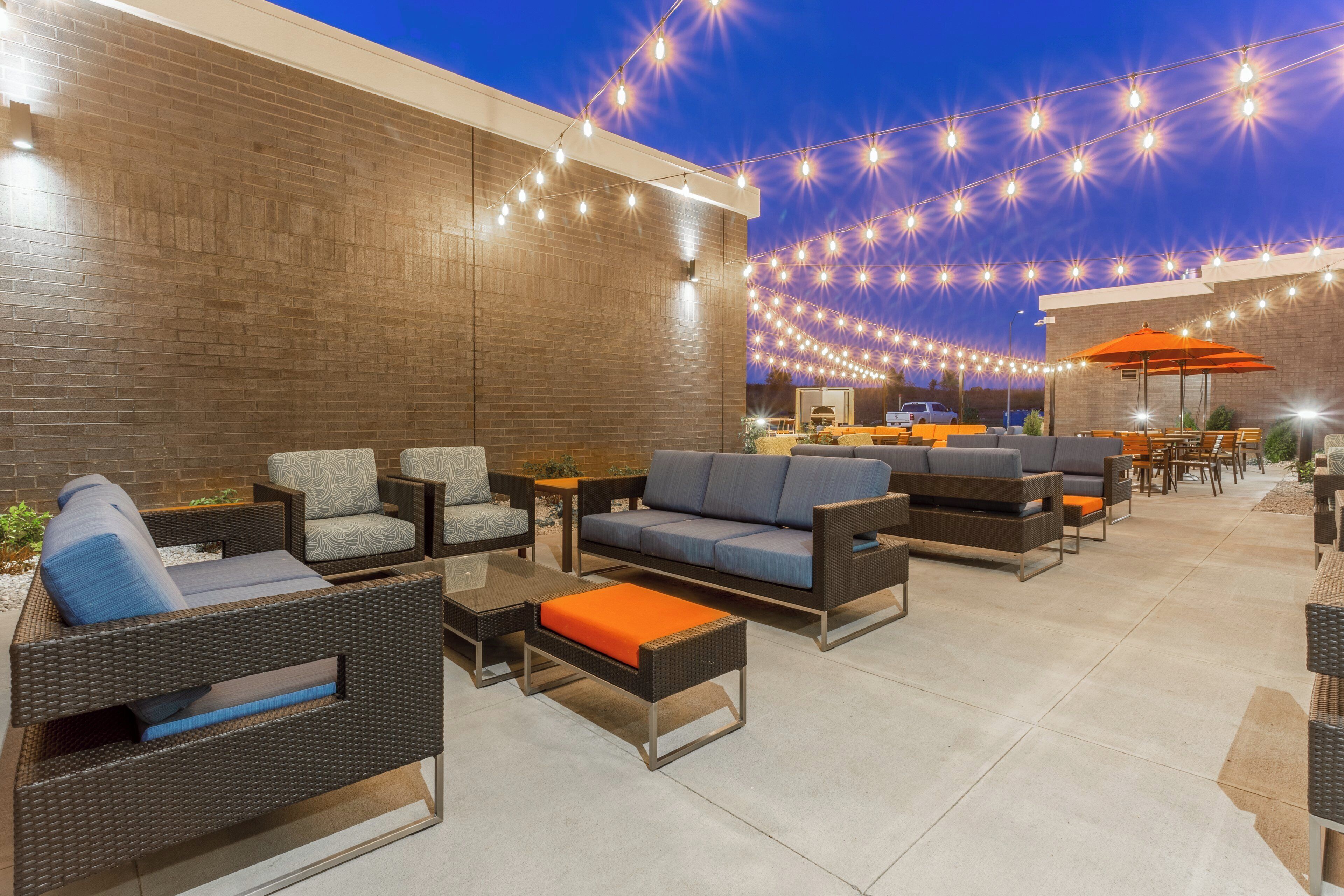 An outdoor seating area with wicker furniture and string lights.