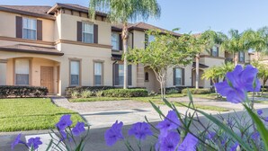 A residential building with a beige facade, dark shutters, and a well-maintained lawn.