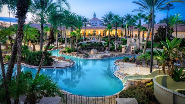 A resort with a central pool, palm trees, and a building with a dome roof.