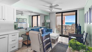 Ein modernes Hotelzimmer mit Balkon, einer Couch, einem Schreibtisch und einem Deckenventilator.