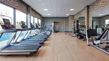 Un gimnasio con cintas de correr, bicicletas estáticas y máquinas de pesas.
