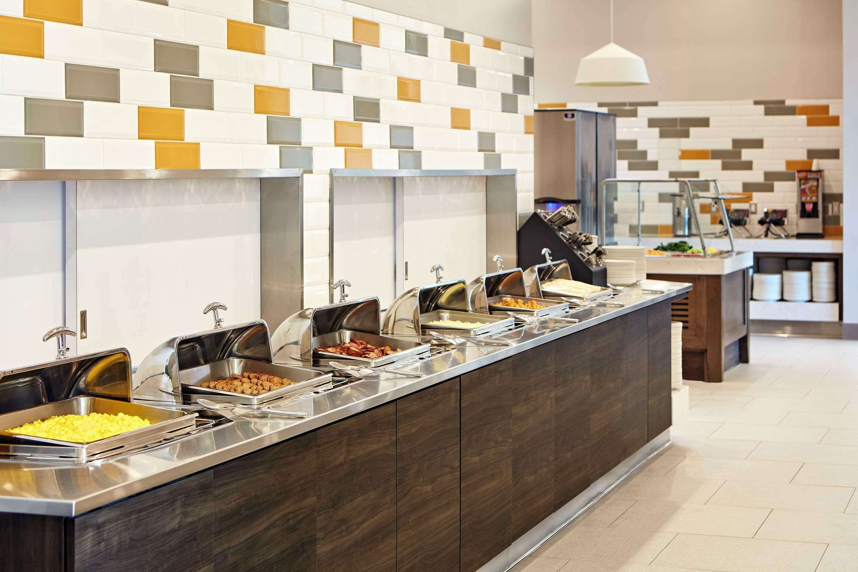 Un buffet avec plusieurs présentoirs de nourriture, un revêtement mural moderne en carreaux et un design épuré et contemporain.