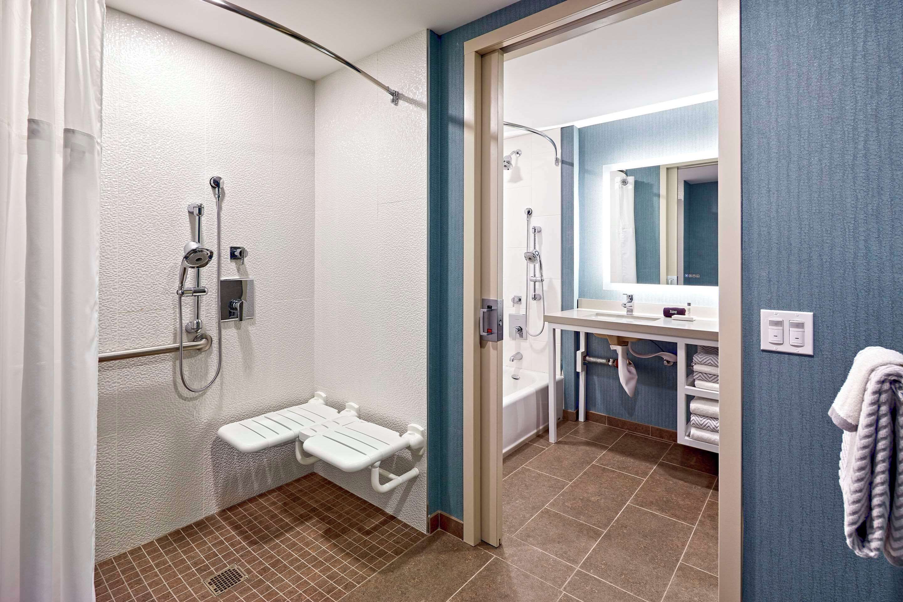 A bathroom with a shower, a bathtub, a sink, and a towel rack.