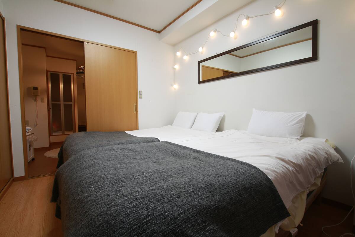 A bedroom with two beds, a large mirror, and string lights.
