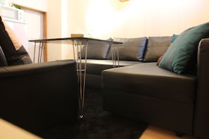 A modern living room with a sectional sofa, a small coffee table, and a dark carpet.