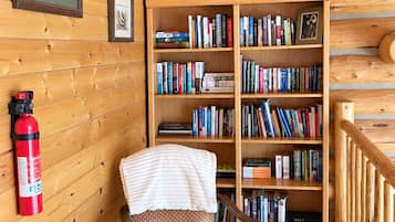 A wooden interior with a chair, a bookshelf, and a fire extinguisher.