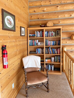 Een houten interieur met een stoel, een boekenplank en een brandblusser.