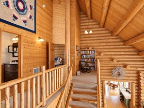 Ein rustikales Holzhaus-Interieur mit einer Treppe, einem Bücherregal und einem Essbereich.
