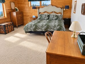 Een kamer met houten vloeren, een bed, een kaptafel en een tafel met een lamp.