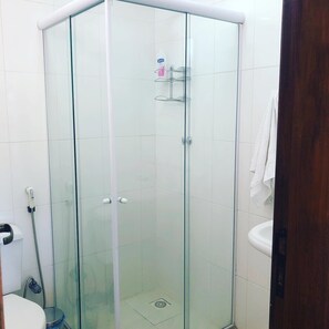 Bathroom features a glass-enclosed shower stall with handheld showerhead and wall-mounted faucet.