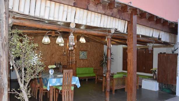 Un comedor de madera con una mesa y sillas, un sofá verde y lámparas colgantes.