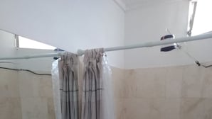 Un baño con lavamanos blanco, cortina de ducha y paredes con azulejos.