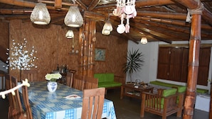 Un comedor con una mesa preparada para dos personas, rodeada de sillas de madera y un sofá verde.