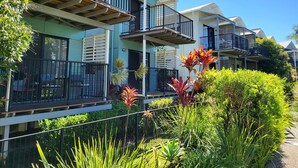 A modern residential building with multiple balconies, large windows, and lush greenery. - Noosa Holiday Accommodation (Tewantin)