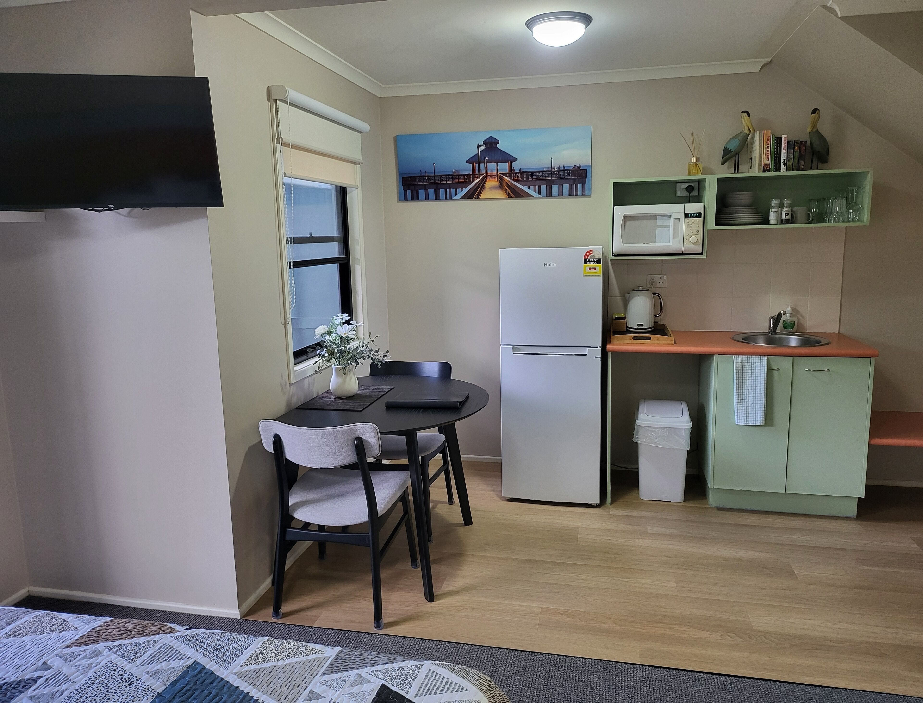 A compact kitchen with a dining table, chairs, a refrigerator, a microwave, and a sink.