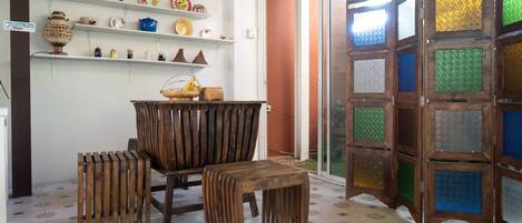 A room with a wooden bench, a small table, and shelves with decorative plates and vases.