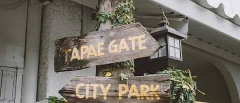 A wooden signpost with directional signs for 'Night Market,' 'Tapae Gate,' 'City Park,' and 'Air Port.'