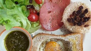 A plate with a sandwich, a slice of bread with an egg, a small bowl of sauce, and a side salad.