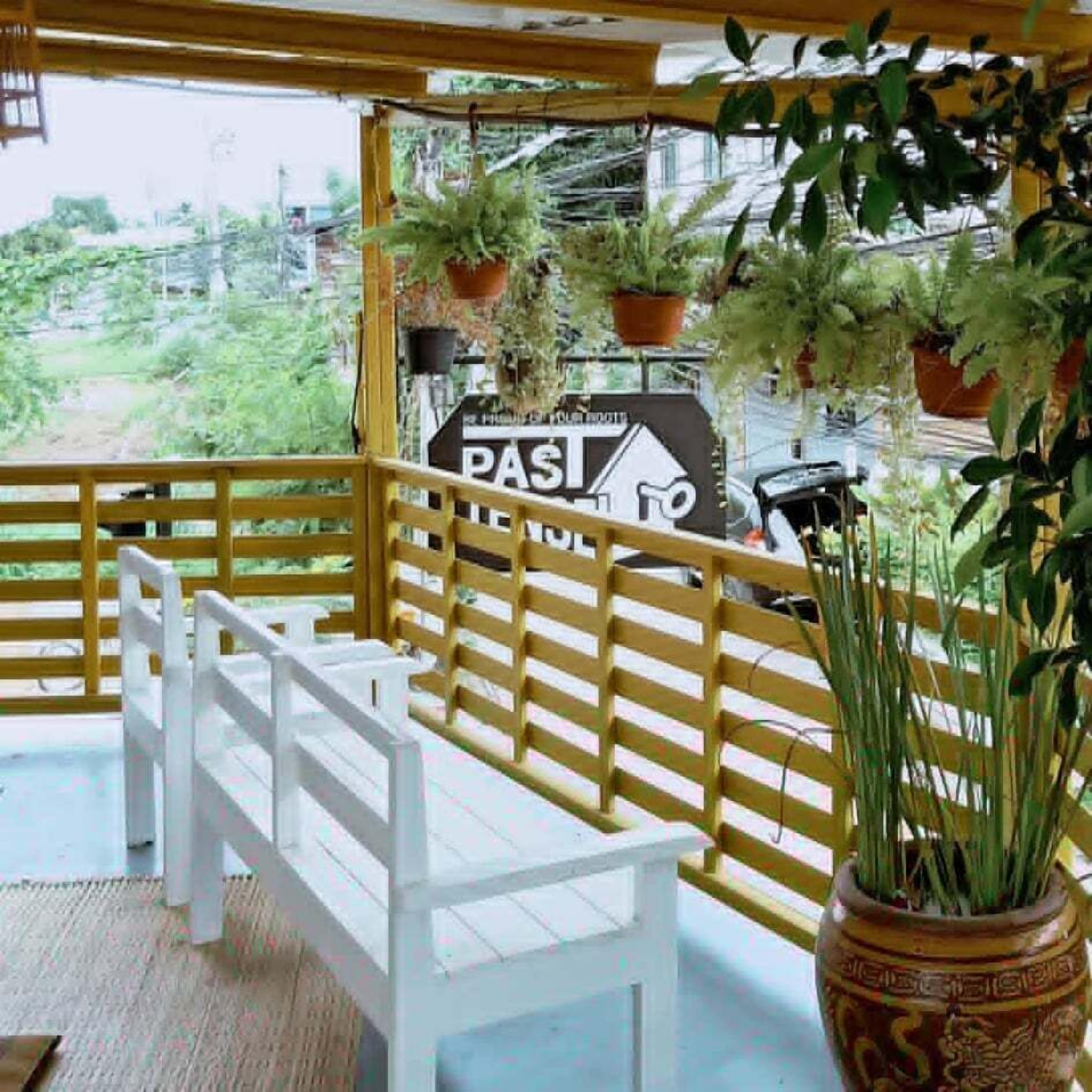 A balcony with a white bench, a wooden railing, and potted plants.