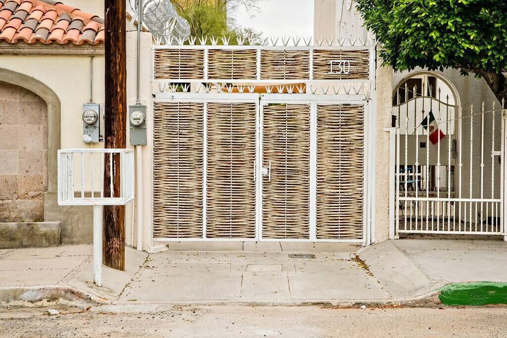 A gated entrance with a metal gate and a white fence.