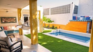 A modern outdoor living area with a pool, a hammock, and a seating area with cushions. - Walk to malecón, private Pool and Garden (Zona Central)