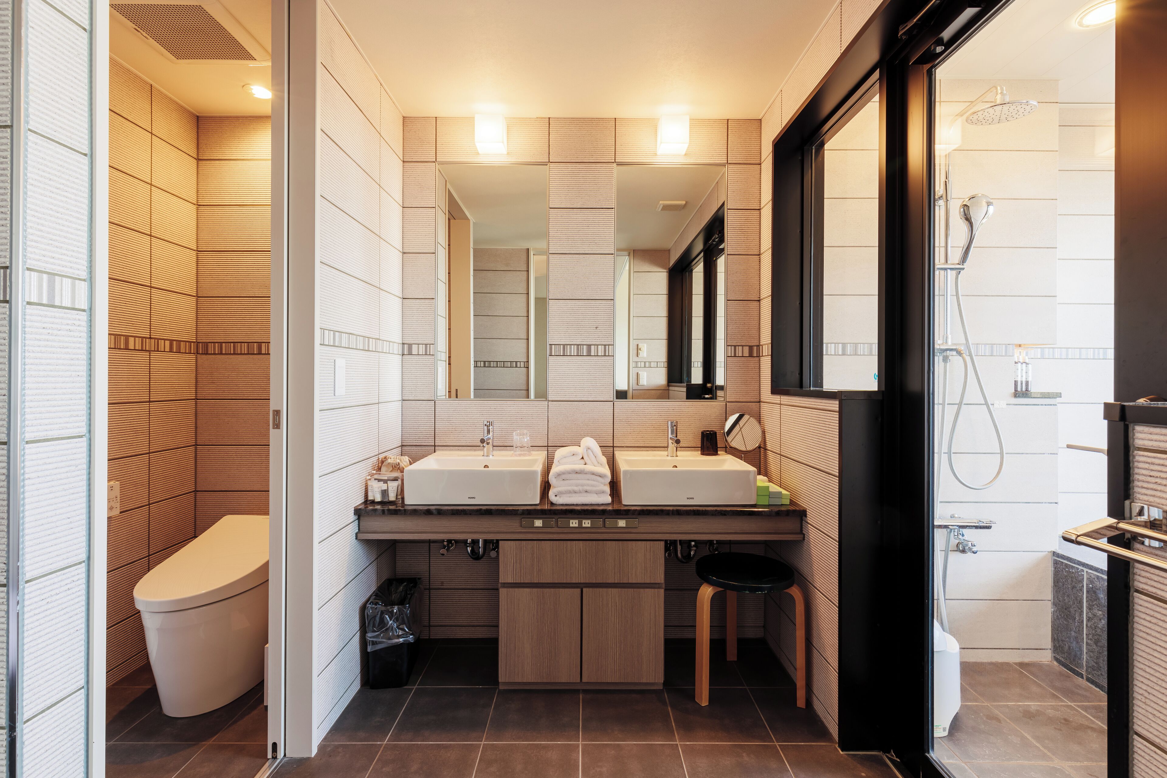 Un baño moderno con dos lavamanos, un inodoro y una ducha.