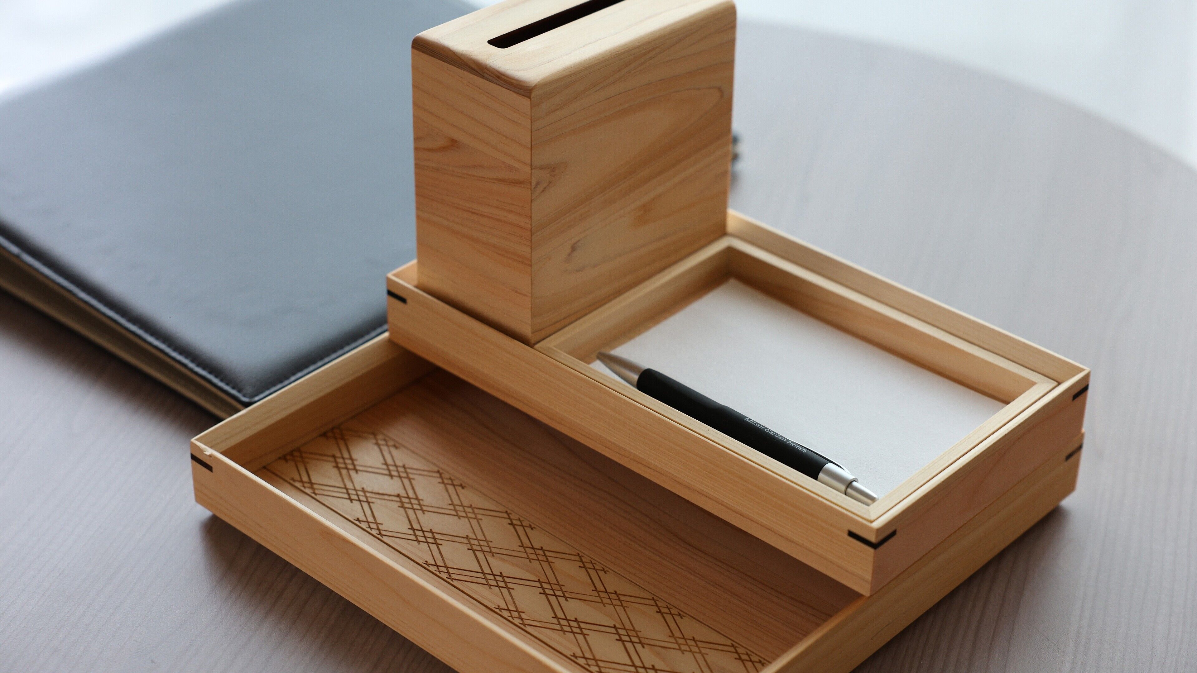 A wooden box with a pen inside, placed on a surface next to a laptop.