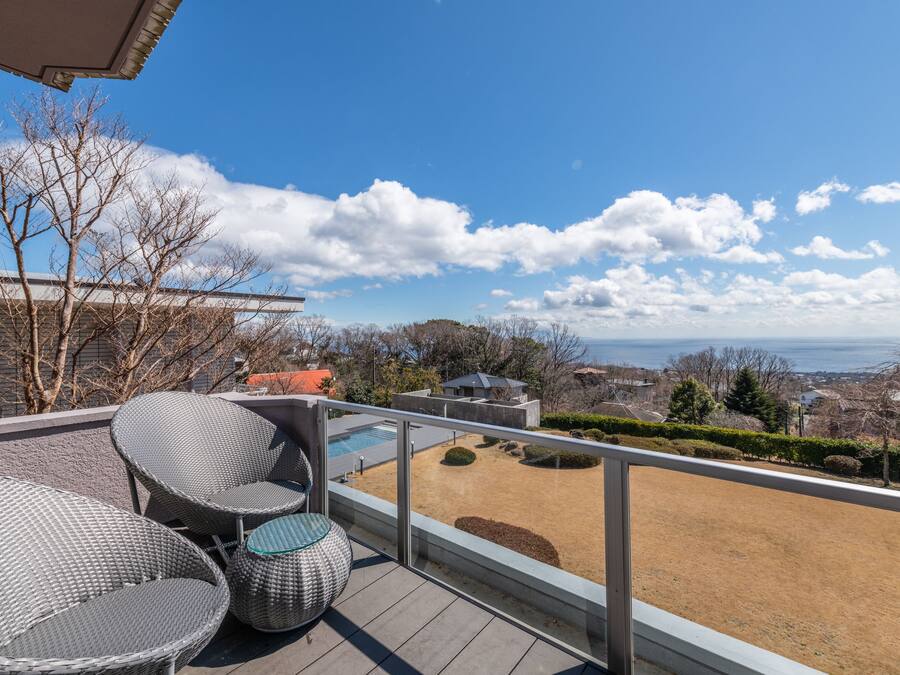 A balcony with wicker furniture, a view of the sea, and a clear sky.