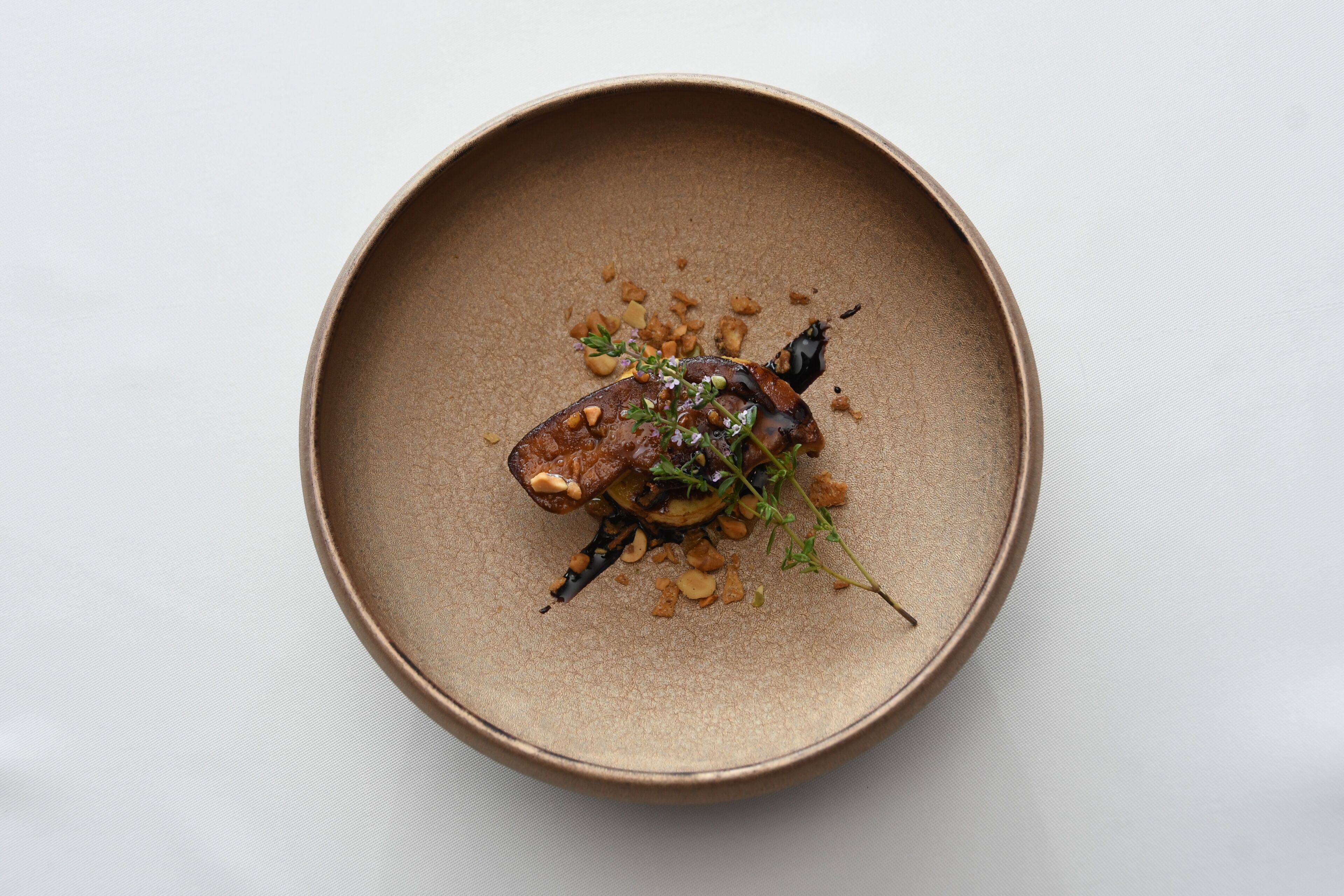 A round, brown ceramic plate with a food arrangement.