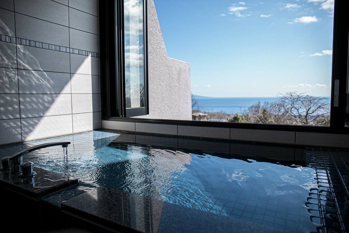 A modern indoor swimming pool with a clear view of the sea through large windows.