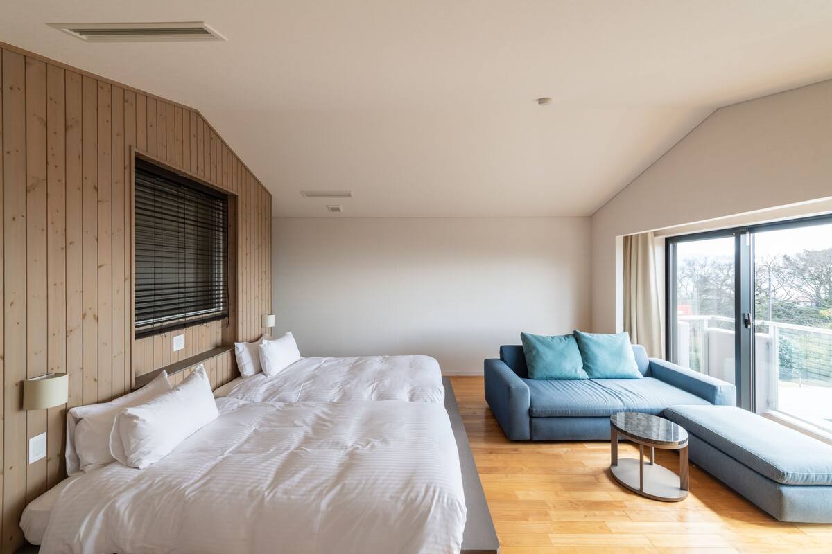 A modern bedroom with a large bed, a sofa, and a small table.