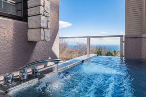 A spa pool with a view of the ocean, a stone wall, and a modern faucet. - the salon Izu Kogen Hotels & Resort (Ito)