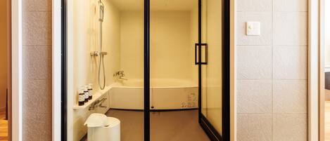 A modern bathroom with a glass-enclosed shower, a bathtub, and a toilet.