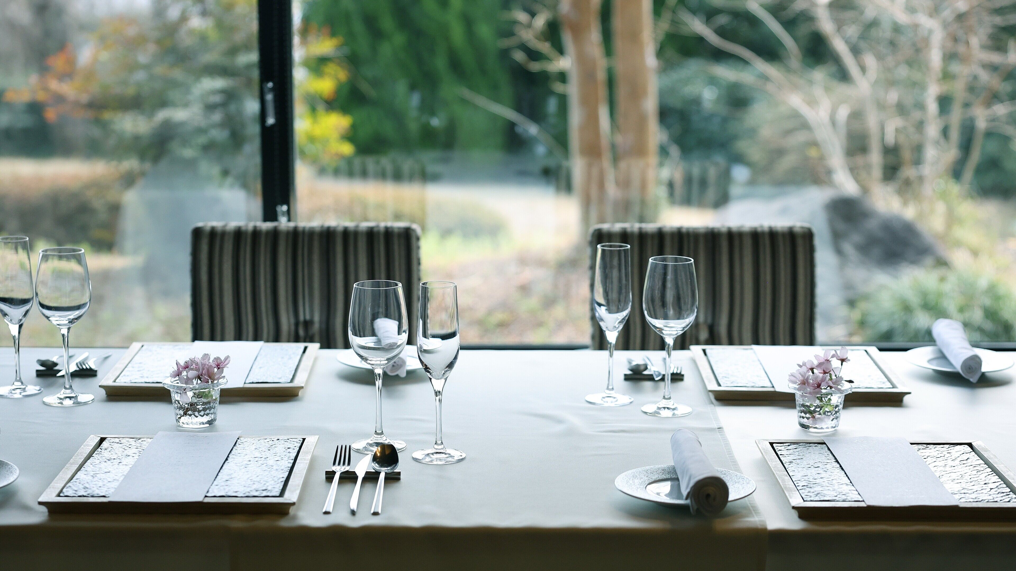 A dining table set for four with wine glasses, cutlery, and a menu.