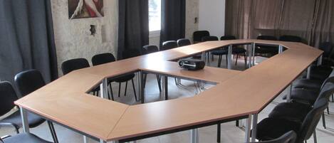 A conference room with a long table, black chairs, and a projector.