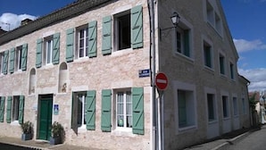 Un bâtiment à deux étages avec des volets verts, un panneau indiquant « accès interdit » et un lampadaire.