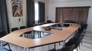 Une salle de conférence avec une longue table, des chaises noires et un projecteur.