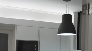 A compact kitchen with white cabinets, a built-in oven, and a hanging pendant light.